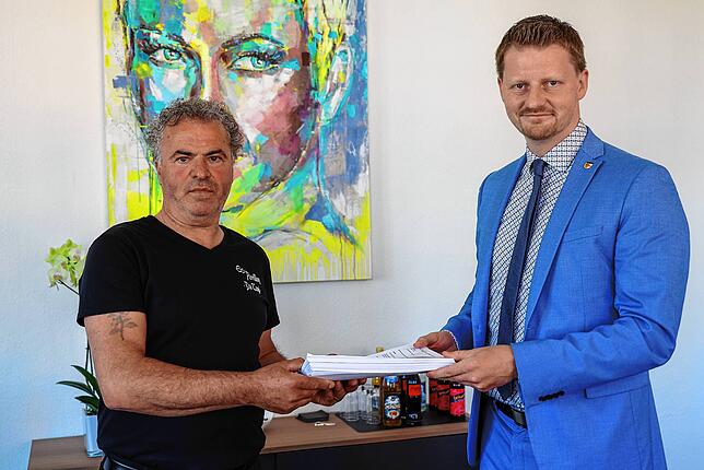 Gastronom Antonio Nadile (links) überreicht OB Simon Gröger die Petition zum Erhalt seiner Pizzeria und Eisdiele mit insgesamt 3187 ...