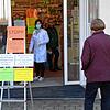 Eine Mitarbeiterin der Einhorn-Apotheke steht im Eingangsbereich und informiert die Kunden über Coronavirus-bedingte Sicherheitshinweise.