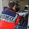 Ein Notarzt zieht eine Krankenliege aus einem Rettungswagen.