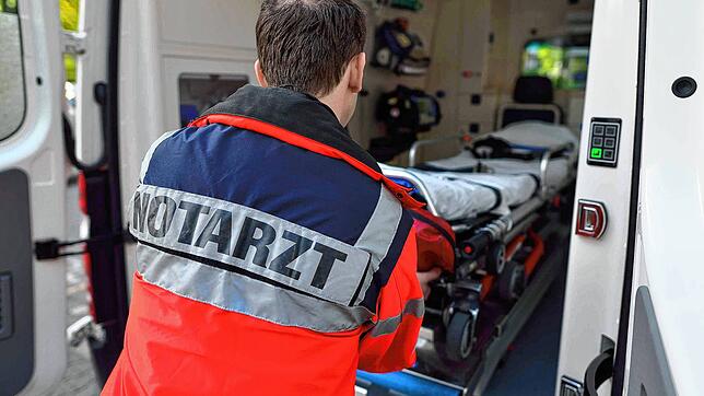 Ein Notarzt zieht eine Krankenliege aus einem Rettungswagen.