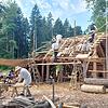 Berufsschüler aus Reutlingen helfen beim Bauen des Dachstuhls. Sie tragen ihre Handwerkskluft mit Hose und Weste, die Ehrenamtlichen und ...
