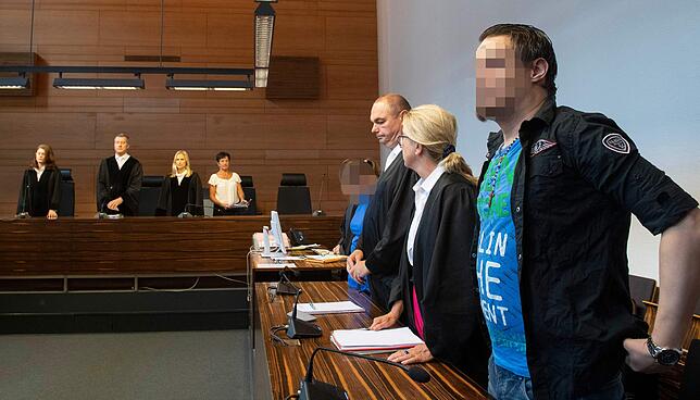 Die beiden Angeklagten stehen im Gerichtssaal neben ihren Verteidigern