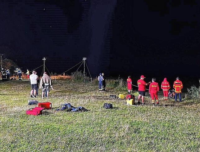 DLRG-Helfer stehen am Samstagabend in einem ausgeleuchteten Bereich des Riedsees.