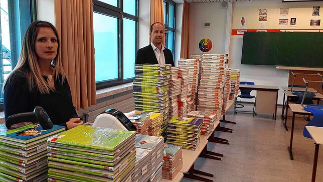 Konrektorin Anne Maier und Realschulrektor Sven Dorn stehen vor den rund 1000 neuen Büchern für die Zehntklässler, die nach dem neuen ...