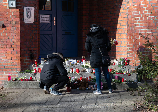 Eine Frau und ein Mann halten vor dem Eingang zu einer Grundschule in Berlin inne. Nach dem Tod einer Elfjährigen sind weiter viele ...
