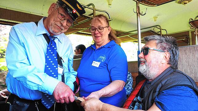 Herbert Homburger (rechts) lässt sich die Fahrkarte per Lochzange vom Museumsbahn-Personal entwerten.