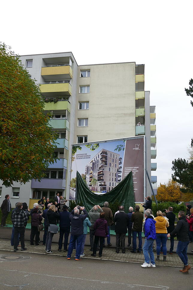 Bewohner des Quartiers zücken die Kamera, als die Tafel mit den kommenden Neubauten enthüllt wird.