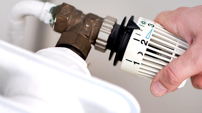 Eine Frau dreht am Thermostat einer Heizung. Sollte zu wenig Gas vorhanden sein, wird bei Haushalten als Letztes abgedreht.