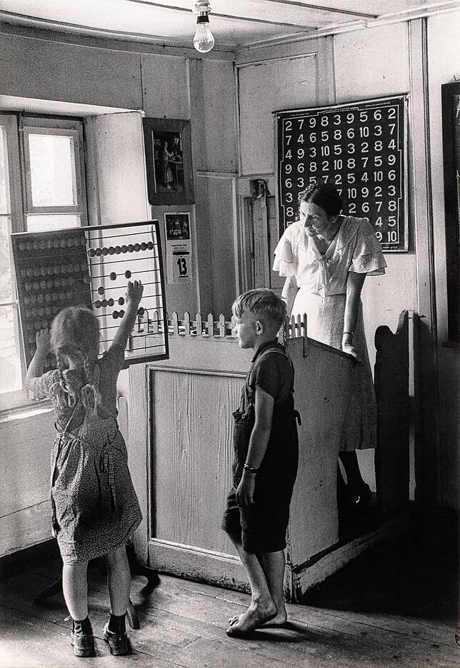 Jakob Tuggener, Lüscherz, 1944: Blick in eine Dorfschule. Das Mädchen am Rechenschieber, der Junge schaut barfuß zu.