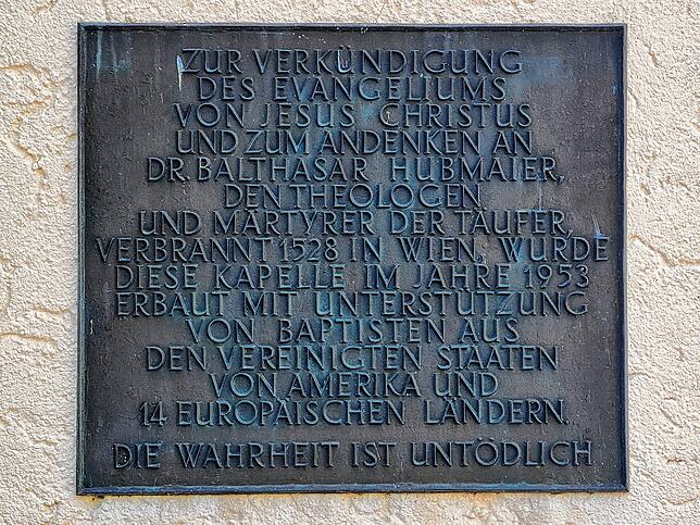 An der Balthasar-Hubmaier-Kirche erinnert eine Tafel an deren Namensgeber.