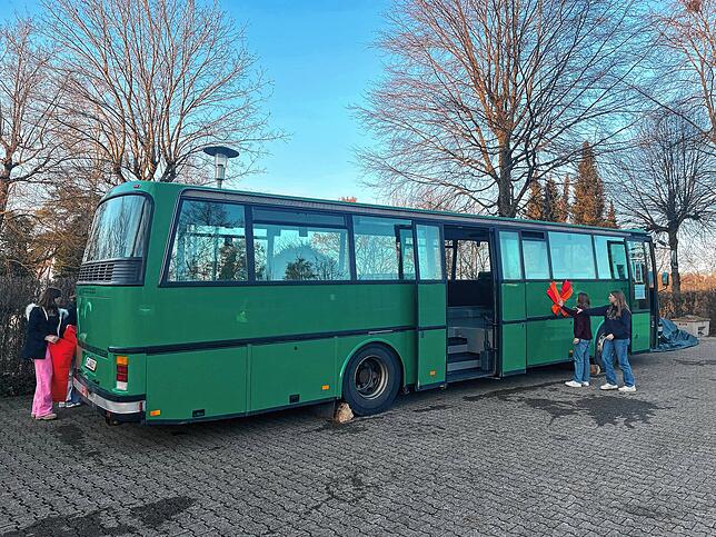 Der grüne Jugendbus auf dem Parkplatz vor der Bergkirche Kadelburg.