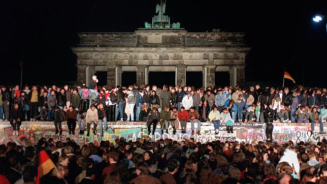 Vor dem Brandenburger Tor am 10. November 1989. Begeisterte Menschen stehen auf der Berliner Mauer. Sie war an dieser Stelle viel ...
