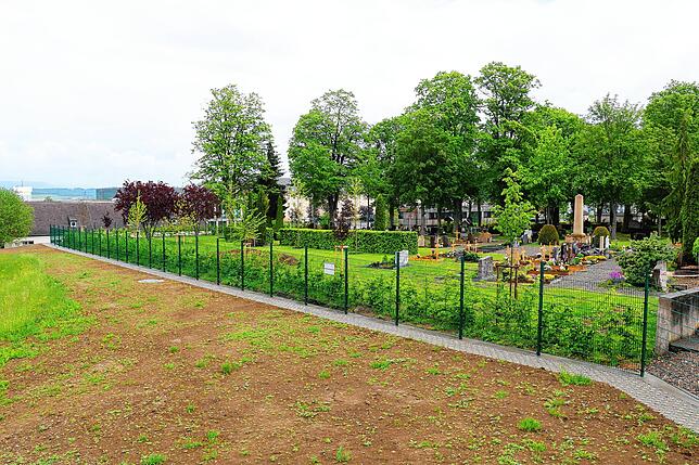 Abschnitt zwei des neuen Kasernenzauns ist fertig: Es ist ein grün lackierter Stabgitterzaun, der auf drei Seiten den Friedhof umschließt.