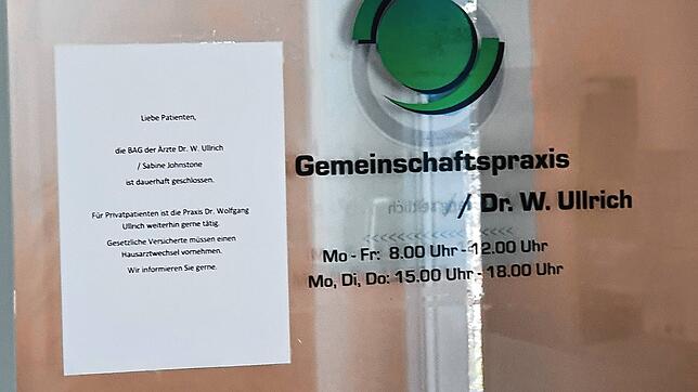 Auf einem Zettel wird den Patienten von Sabine Johnstone mitgeteilt, dass sie sich einen neuen Arzt suchen müssen. Am Schild der ...