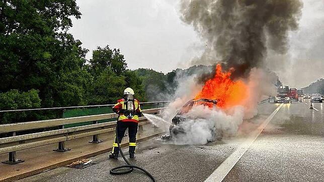 Ein Feuerwehrmitglied löscht das brennende Fahrzeug.
