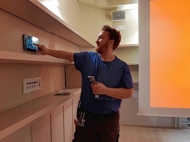 Moderne Technik: Joa Agus, Elektroniker für Gebäude und Energietechnik, fährt im Veranstaltungsraum die Leinwand (im Bild rechts) ...