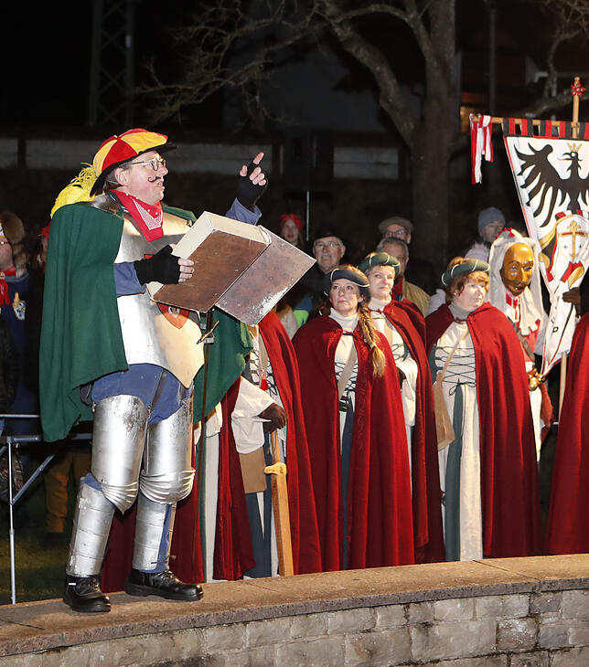 Ortsrichter Dedelius (Wolfgang Gut) verliest die Anklage, im Hintergrund die Burgfräulein von Allmendshofen.