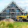 Fast fertig: Ein Bagger nimmt vor einem Neubau letzte Arbeiten vor. Bauherren kämpfen mit steigenden Preisen und unsicheren Fördergeldern.