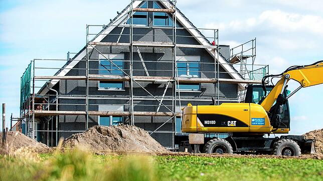 Fast fertig: Ein Bagger nimmt vor einem Neubau letzte Arbeiten vor. Bauherren kämpfen mit steigenden Preisen und unsicheren Fördergeldern.