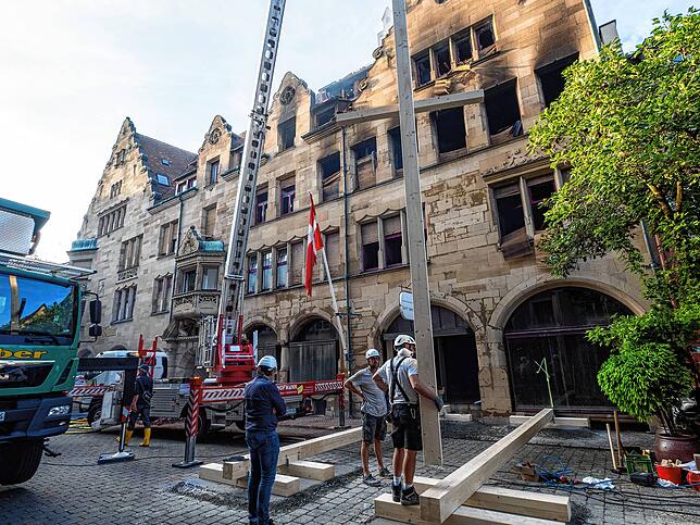 Schließlich werden die großen Holzstützen aufgerichtet und an den richtigen Stellen platziert. Fassade und Giebel bleiben stehen. Die ...