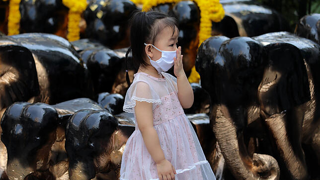 Ein Mädchen trägt einen Mundschutz beim Besuch des Erawan-Schreins. Die thailändischen Gesundheitsbehörden haben die ...