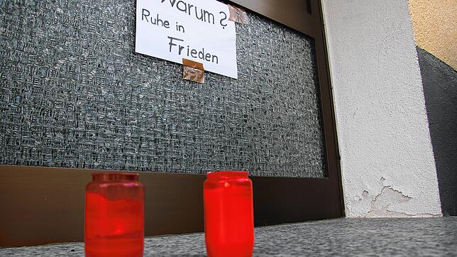 Am Eingang zum Haus der Getöteten stehen kurz nach der Tat Grabkerzen. An der Tür hängt ein Schild mit der Aufschrift: &bdquo;Warum? ...
