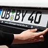 Eine Autofahrerin montiert ein ÜB-Kennzeichen am Heck ihres Autos. Seit Februar 2020 gibt es wieder die Altkennzeichen (Symbolfoto).