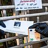 Eine Mitarbeiterin eines Friseursalons in Frankfurt reicht einen &bdquo;Shutdown-Gutschein&ldquo; durch das heruntergelassene Gitter am ...