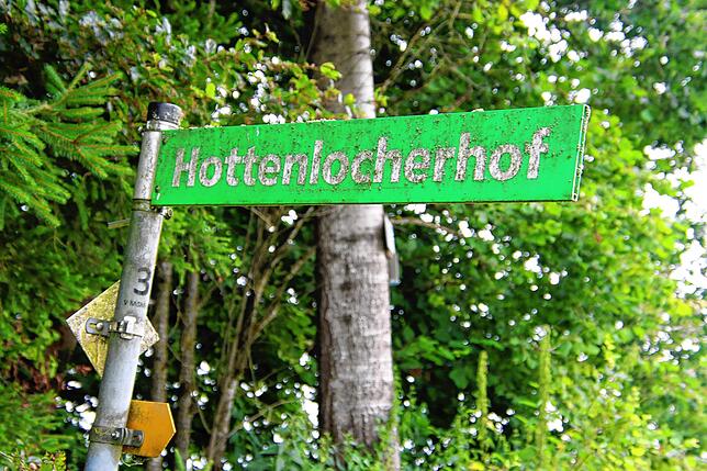 Ein Schild am Wegesrand weist auf den Hottenlocher Hof hin.