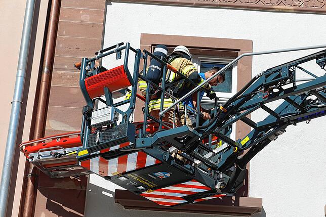 Eine Bahre ist am Korb der Drehleiter befestigt, um eine verletzte Person aus dem Obergeschoss des Gebäudes zu retten.
