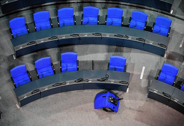 Ein einzelner Stuhl liegt im Plenum im Bundestag vor den Fraktionsreihen der Union. Normaler sollen im deutschen Bundestag 598 ...