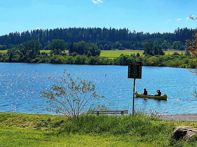 Badegäste sind derzeit nicht im Kirnbergsee zu finden, auf dem See sind zwei Menschen am paddeln.