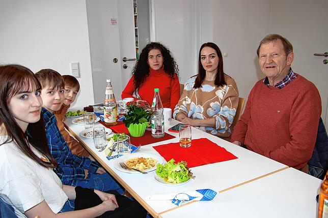 Karl Hermann am Mittagstisch zusammen mit Frauen und Kindern aus der Ostukraine. Um die Sprachbarriere zu überwinden, kommt das Handy ...