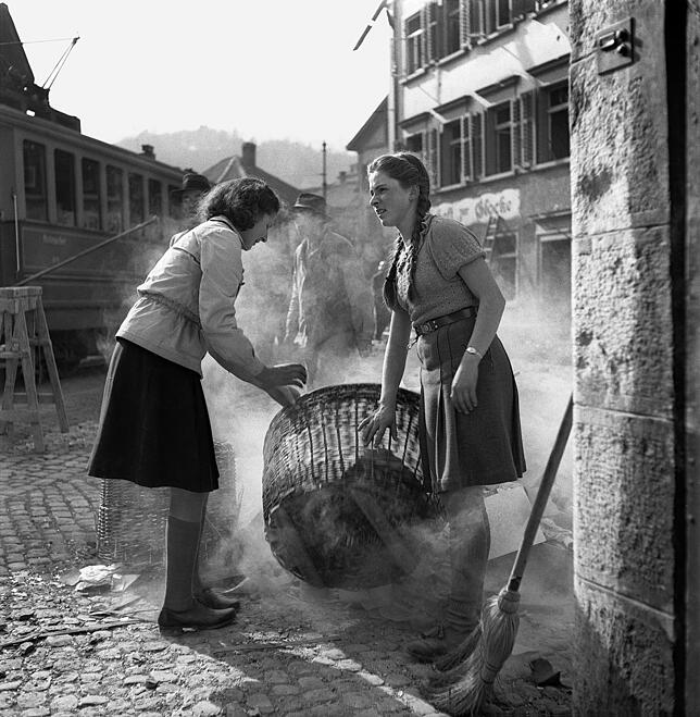 Aufräumarbeiten: Frauen hantieren mit einem Korb, in dem Mauerbruchstücke aufgelesen und gesammelt werden. Auch Kräne und schweres ...