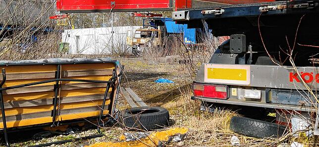 Reifen und alte Sofas liegen ebenfalls auf dem Gelände. Im Hintergrund das ausgebrannte Führerhaus eines Lastwagens.