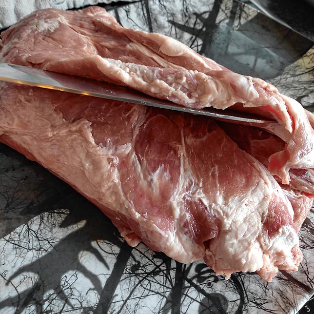 Der Kammbraten muss sorgfältig aufgeschnitten werden, damit später keine Löcher im Fleisch sind und die Füllung nicht seitlich ...