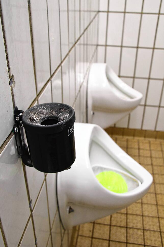 Neben den Pissoirs in der Männertoilette der öffentlichen Toilette bei der Schlossgarage in Tiengen sind Aschenbecher montiert.