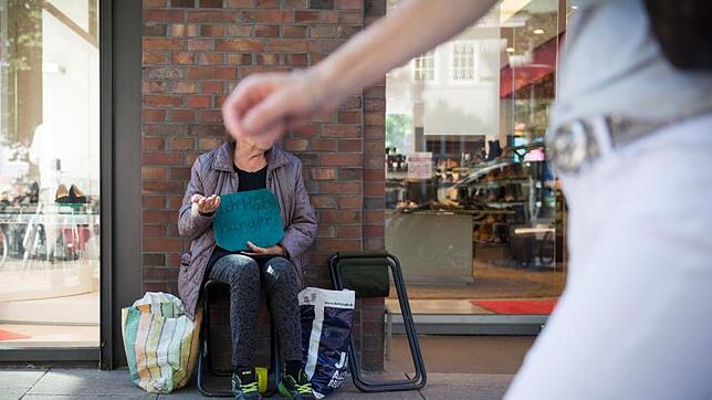 Ein gewohntes Bild in deutschen Füßgängerzonen: Eine Frau hält ein Schild mit der Aufschrift „Ich habe Hunger“.