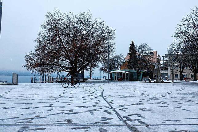 Am Landungsplatz ist nur ein Fahrradfahrer unterwegs. Der Platz ist von einer dünnen Schneeschicht bedeckt.