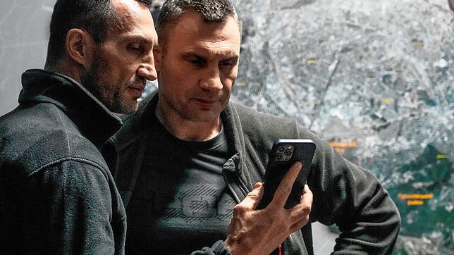 Vitali Klitschko (rechts), Bürgermeister von Kiew, und sein Bruder Wladimir Klitschko schauen auf ein Smartphone im Rathaus in Kiew. ...
