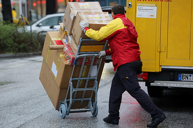 Ein Paketbote von DHL liefert Päckchen aus. Wer in Deutschland ein Paket nach Hause bestellt, könnte dafür langfristig mehr bezahlen müssen.