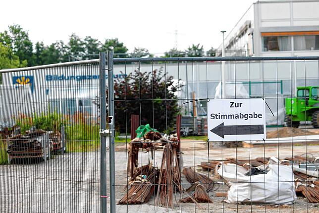 Wegweiser zeigen Wählern entlang der Baustelle des Bildungszentrums den Weg zu den Wahllokalen.