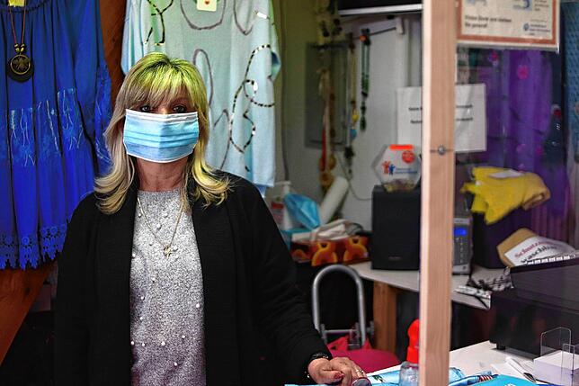 Maria Sostaric mit Maske hinter dem Spuckschutz von „Anna Mode“. Ihre Maske ist ihr noch ein bisschen zu groß, sie will sich ...