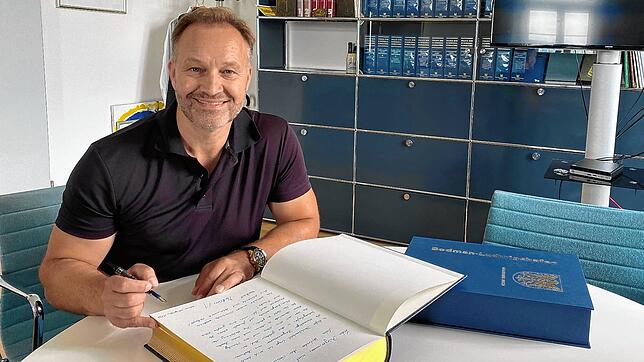 Matthias Weckbach trägt sich als erster in das neue Goldene Buch der Gemeinde Bodman-Ludwigshafen ein. Er sitzt dabei am ...