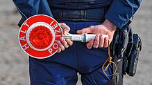 Ein Polizist hält eine Halte-Kelle.