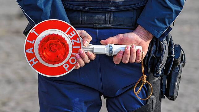 Ein Polizist hält eine Halte-Kelle.