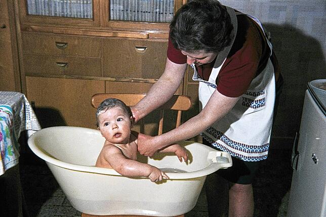 Bis in die 60er-Jahre waren Wohnküchen für Kinder gleichzeitig das Badezimmer. Hier wäscht Oma ihr Enkelkind in einer Plastikwanne. ...