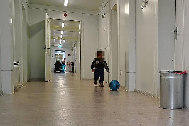 Ein Kind in der Flüchtlingsunterkunft in der Badstraße spielt im Gang mit einer Weltkugel.