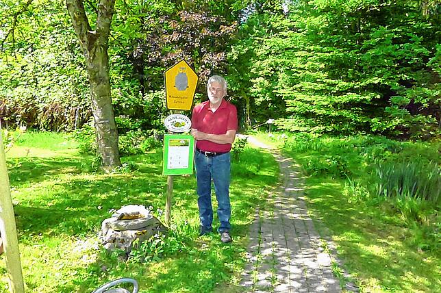 Nicht ohne Stolz präsentiert Rolf Servos die Auszeichnung seines Gartens als Naturgarten. Rechts im Hintergrund durch Pflanzen verdeckt ...