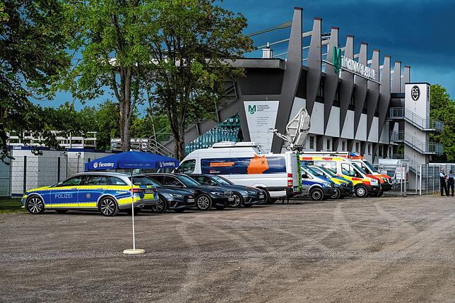 Im abgesperrten Bereich vor der dem Stadion sind unter anderem Fahrzeuge von Polizei und Rettungsdiensten platziert.